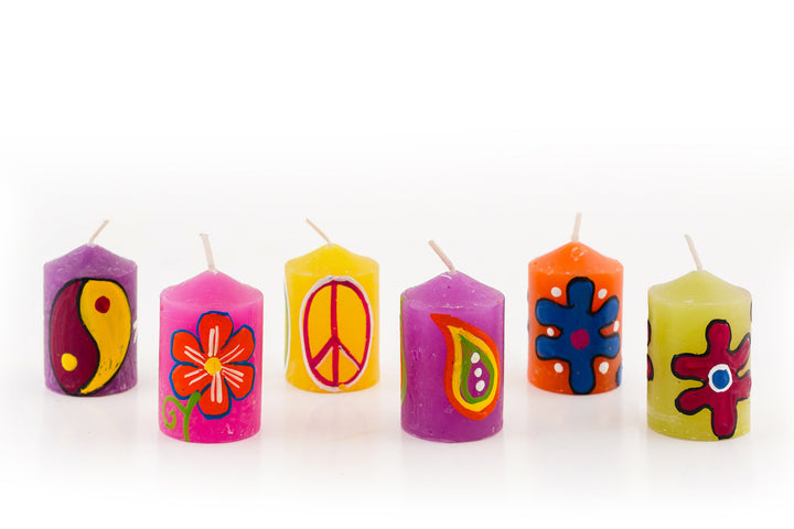 Hippie 2" votives showing 6 designs; purple candle with ying-yang, bright pink candle with orange flower, yellow candle with peace sign, purple candle with  paisley, orange candle with blue 'hippie' flower, green candles with 'artsy' flower.