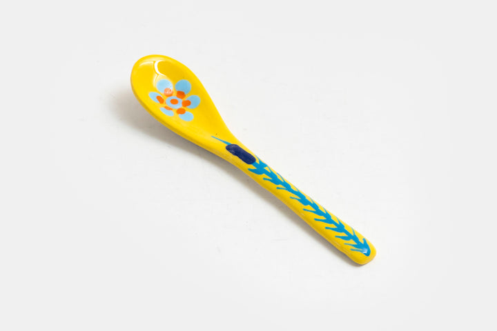 Ceramic small spoon with background color of yellow, detail painted in red, indigo, orange, & baby blue.  Great for condiments. 