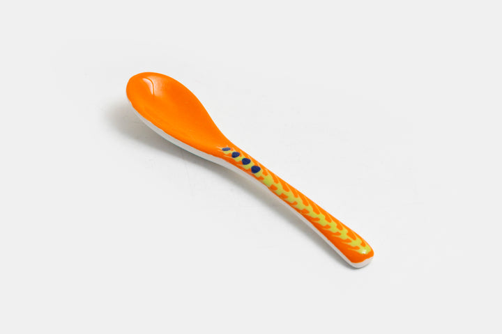 Ceramic small spoon with background color of orange, detail painted in red, indigo, lime green, & baby blue.  Great for condiments. 