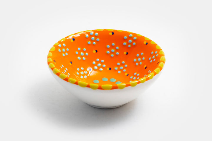 Tiny ceramic bowl, orange background with mixed patterns of dots & stripes in different sizes and colors.