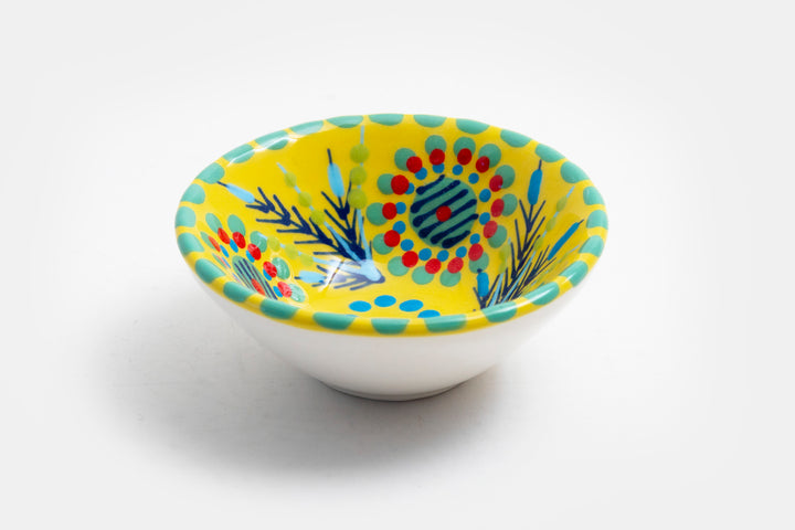 Tiny ceramic bowl, yellow in background with mixed patterns of dots & stripes in different sizes and colors.