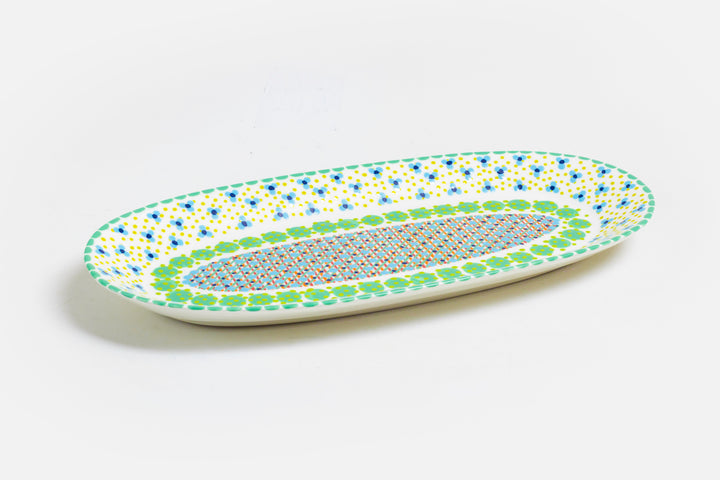Serving platter with white base color, painted with dots, stripes and flowers in indigo, orange, yellow, baby blue, and touches of red. Microwave and dishwasher safe.