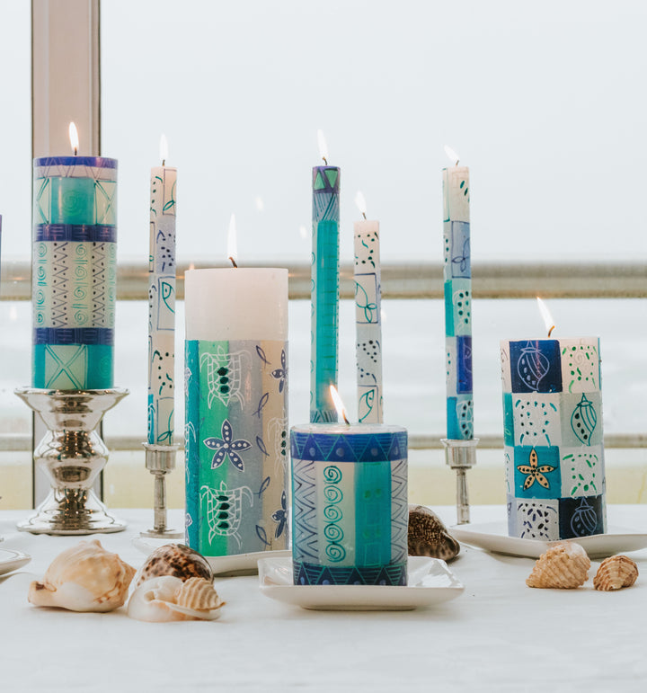 Lifestyle photo of Arniston tapers an pillars mixed with Blue & Green candles on a dinner table.  Sea shells on table - very fun, sea side feeling!