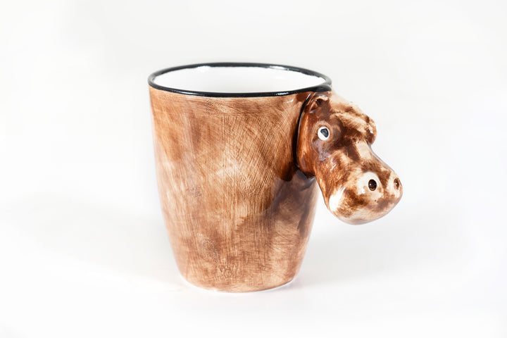 Front view of the ceramic coffee mug with a hippo head for the handle. Painted in giraffe skin colors of yellow & brown with white inside the mug.