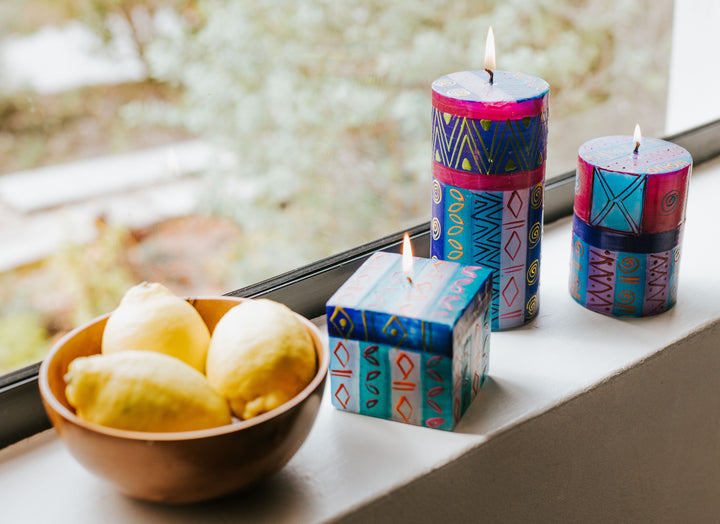 Lifestyle shot of Blue Moon 3x4 pillar, 3x6 Blue Moon pillar and 3x3x3 Blue Moon cube.  Burning on a window ledge with a bowl of lemons, bringing out the touches of yellow on the candles.  