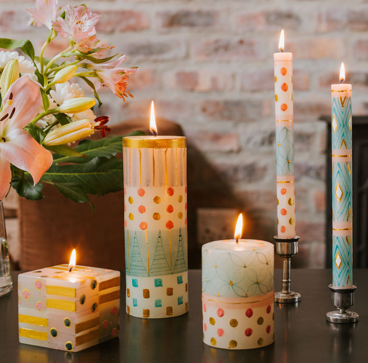 Lifestyle photo of the Delight collection.  Pillars, cubes and 2 tapers, burning with some pink lilies along side.  So soft and so beautiful!