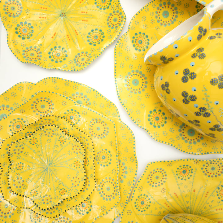 Tulip cocktail plate stacked on side plate, on dinner plate  on dinner plate large with yellow background, dark green and indigo floral design.  This is a sample of the other colors available for the ceramic dinner set.
