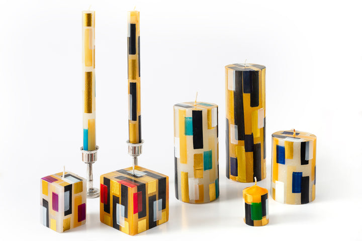 Klimt Candle Collection.  Cream candles with touches of black, gold along with hints of blue, red, green, & turquoise make them a contemporary choice.  The photo is a taper candle pair in pewter taper holders, 2" cube and 3" cube candles, 3x4 Pillar, 3x6 Pillar and 3x8 Pillar candles, with one 2" votive. 