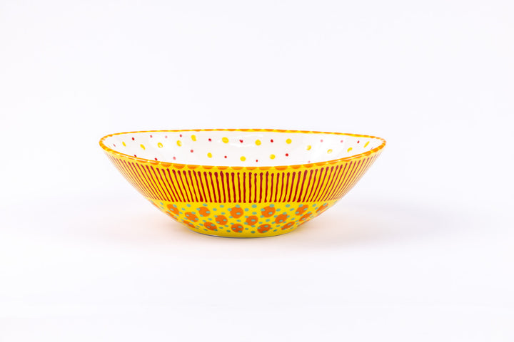 Oval ceramic serving bowl with yellow base color. Red, orange, and green dots & stripes on top.  Inside is white with yellow & red dots.  Very fun!