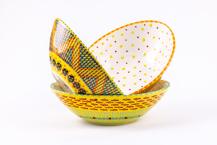 3 ceramic stacked oval serving bowls with Yellow base color with dots & stripes on top in colors of red, orange, turquoise & green. Inside of one bowl is sweetly painted with yellow & red dots.