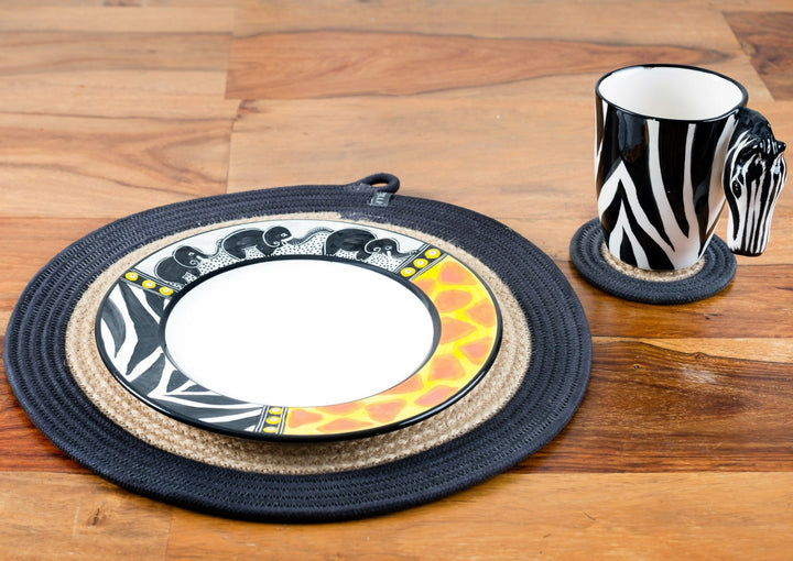 Ceramic Zebra coffee mug. White mug painted in zebra print with a zebra head for the handle! White inside. Along side the African Animal print plate. Both on woven mats on a table. Very cute pair as the zebra print is on both the mug & the plate