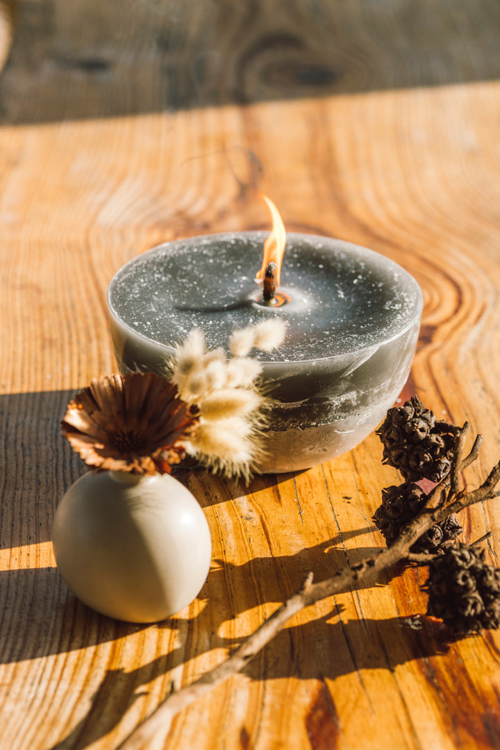 Charcoal outdoor bowl candle burning on a wooden plank. 