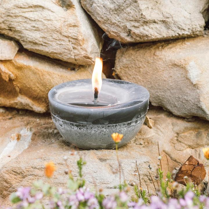 Charcoal outdoor bowl candle burning in the garden alongside the rocks.