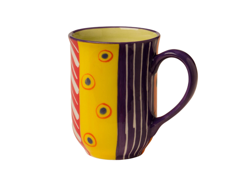 Carousel hand painted ceramic mug - side 1. Large stripes of color; yellow, purple, orange, with white stripes and orange dots.  Yellow inside. Colorful,  whimsy & fun. Fair Trade!