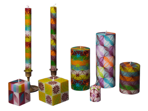 Set of 7 candles; taper pair, cubes, pillars, votive. White base with green, orange, turquoise, and lavendar stripes. Overlay of pigment colors with a variety floral and leaf designs.