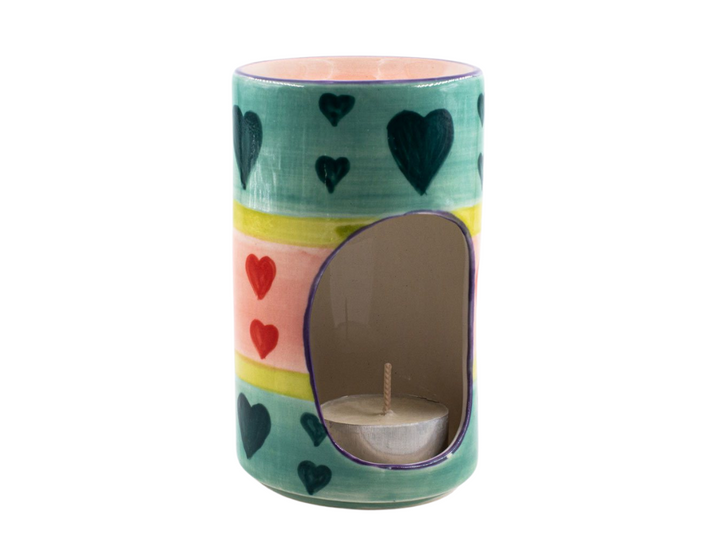 The other side of the Pastel Heats Ceramic Burner. Tea light in bottom that glows through the opening while scent burns on top. Colorful pastel hearts in green, blue and pink design pattern painted on side. Fair Trade.